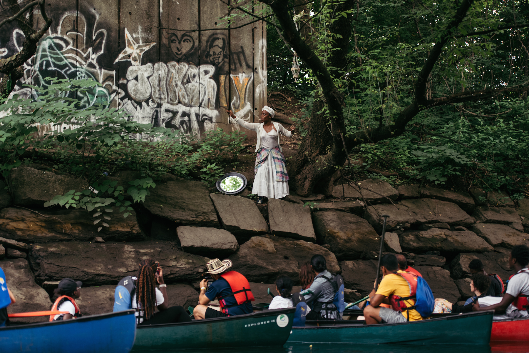 Paloma McGregor IMG Audrey Hailes with audience members in canoes in the river below in Building a Better Fishtrap / from the riverʼs mouth, on the Bronx River. 